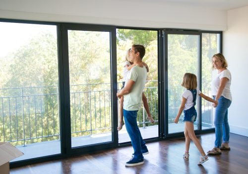 happy-father-with-daughter-standing-near-open-balcony-and-smiling